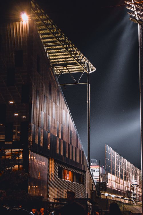 Free Night view of a modern stadium exterior with lighting and architectural details. Stock Photo