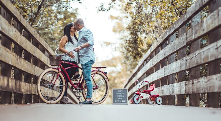 Couple Kissing While Holding A Bike