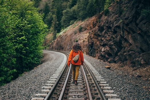 A woman walking on a railroad track through scenic nature in Northern California, embracing freedom and adventure.