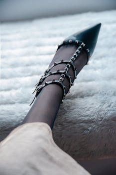 Close-up of an elegant studded high heel shoe on a textured white background, ideal for fashion concepts.