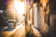 温暖的阳光沐浴着伊斯坦布尔的街景，街上有车辆驶过，墙壁纹理丰富