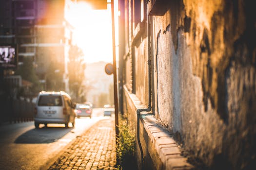 温暖的阳光沐浴着伊斯坦布尔的街景，街上有车辆驶过，墙壁纹理丰富