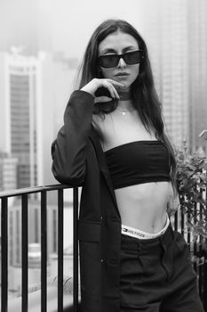 Fashion model in monochrome posing confidently on a rooftop with city skyline backdrop.