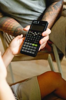 Two people exchanging a calculator, showcasing modern digital learning tools.