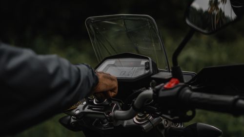 Free A detailed shot of a motorcycle handlebar with a rider's hand and a visible speedometer. Stock Photo