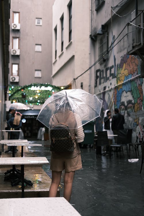 Woman with an Umbrella Waiting on an Alley