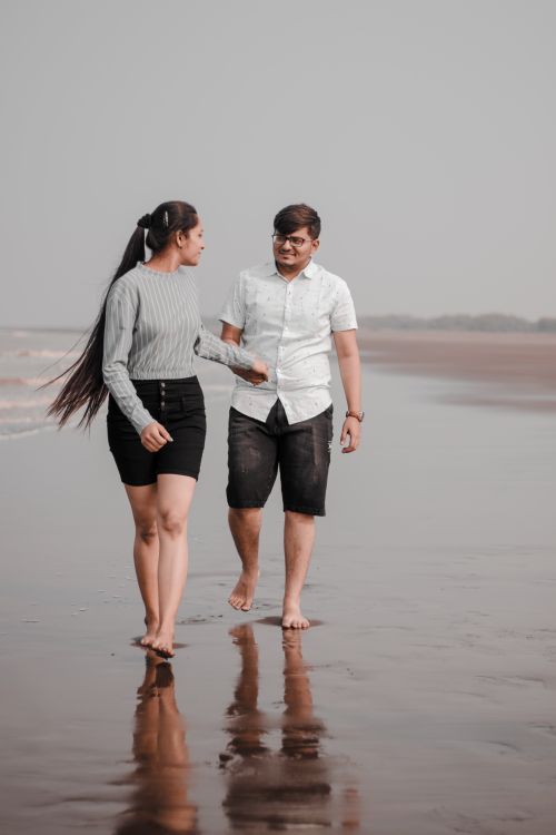 Free A couple enjoys a romantic walk on a serene seaside, showcasing love and tranquility. Stock Photo