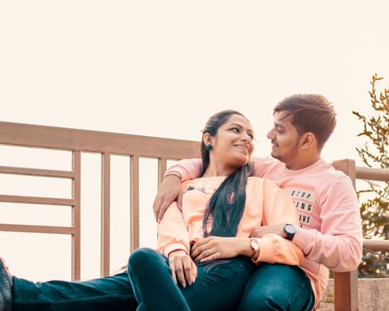 A couple enjoying a sunny day outdoors, sitting on a bench with affection. - Fotografer Sidoarjo