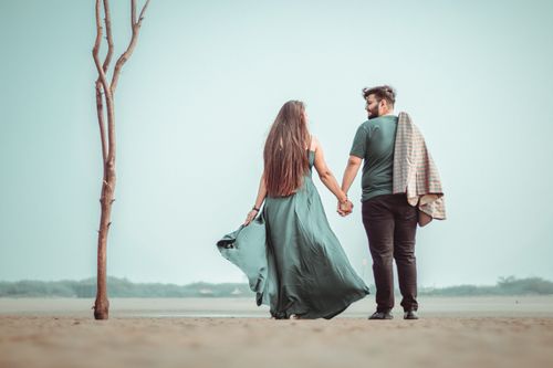 Free A couple holding hands and walking on a serene beach, symbolizing love and connection. Stock Photo