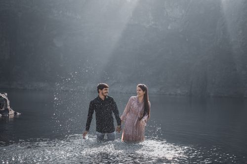 Free A romantic couple holding hands and splashing water in a serene lake setting, embracing love and connection. Stock Photo