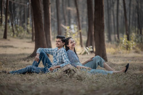 A Man and a Woman Sitting on Ground Beside Trees
