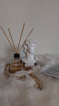 A stylish setup featuring a bust sculpture, fragrance diffuser, and plush textures for a cozy home ambiance.
