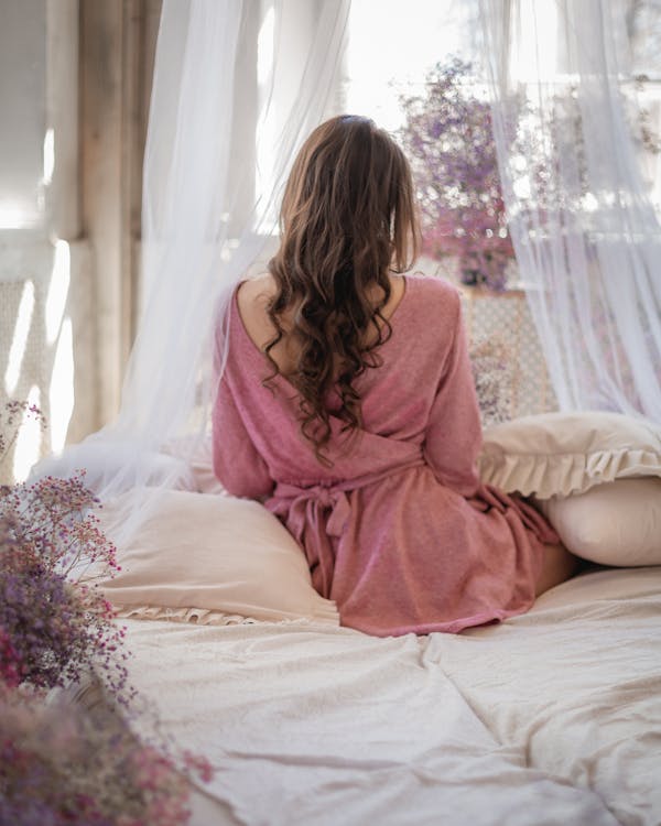 床上的粉红色连衣裙的女人