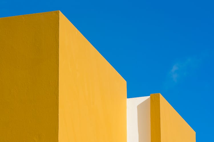 Top Of Vibrant Yellow Building Against Blu