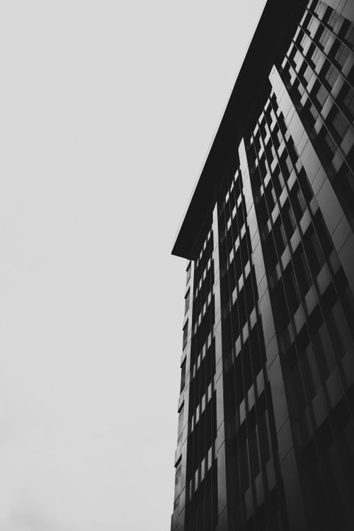 Free Low angle black and white shot of a skyscraper against a blank sky, emphasizing modern architecture. Stock Photo