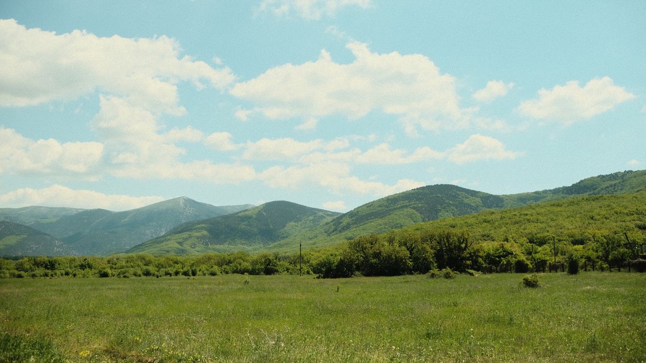 A Green Grass Field Near Green Mountain Under the Blue Sky · Free Stock ...
