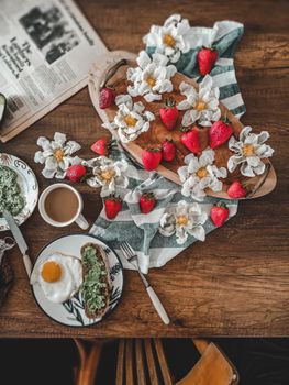 A rustic breakfast scene with strawberries, toast, and tea on a wooden table.