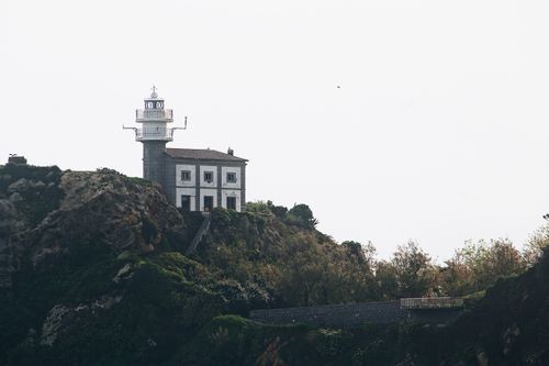 Free Lighthouse perched on a rocky coastline in Spain, offering a scenic travel destination. Stock Photo
