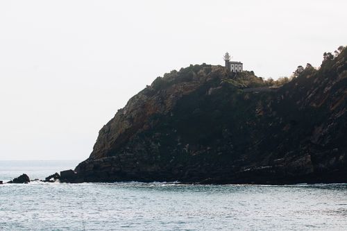 Free A picturesque lighthouse atop a rugged Spanish cliff by the tranquil sea. Stock Photo