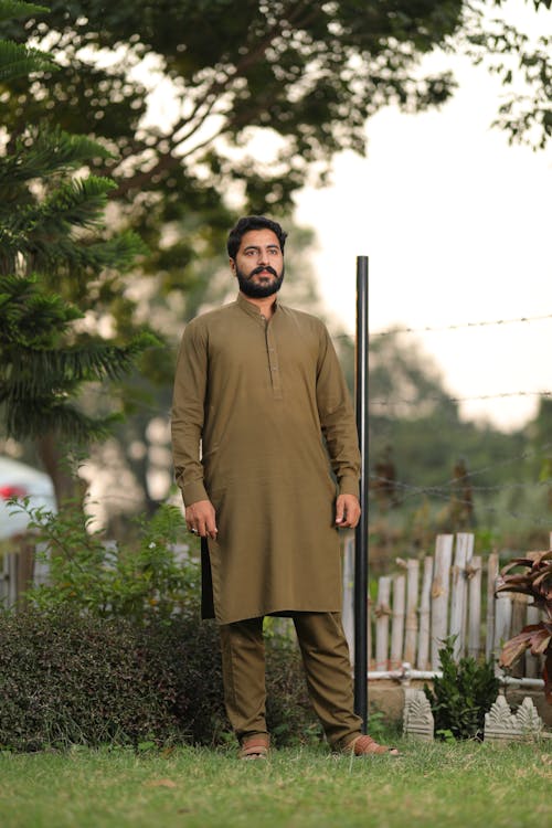 Man in Traditional Clothes Standing on Green Grass