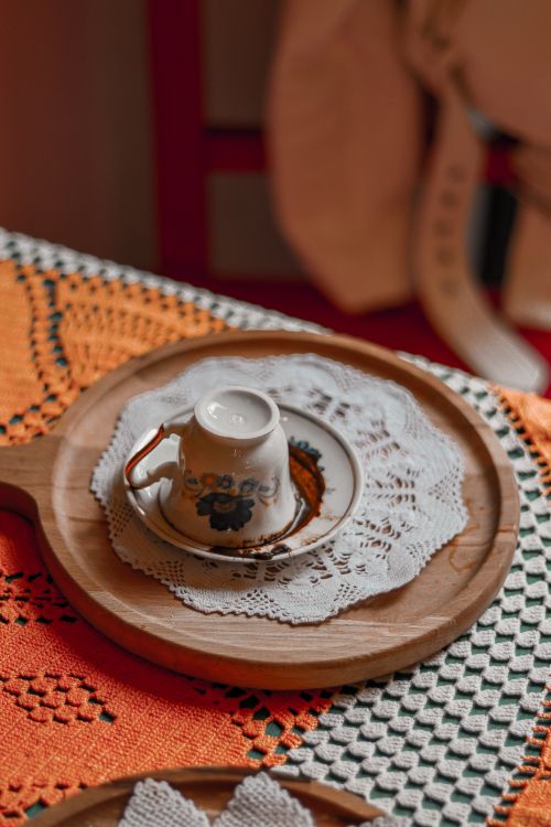 Free An upside-down porcelain teacup on a lace doily atop a wooden tray. Stock Photo