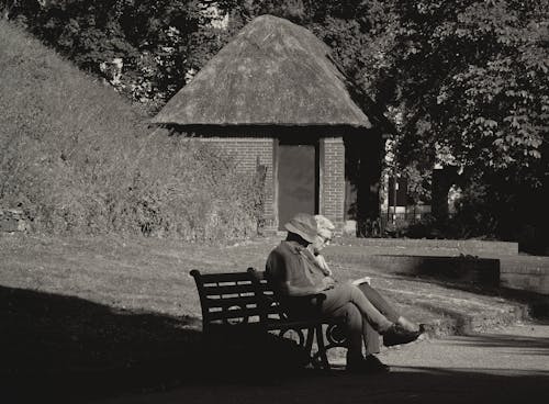 Grayscale Photo of Two People Sitting on the Bench