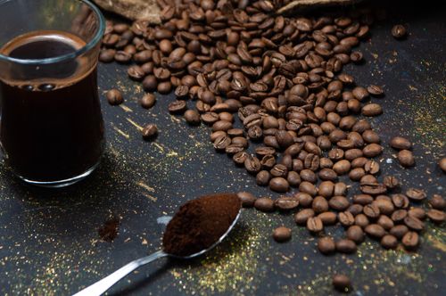Free Roasted coffee beans and a fresh brew in a glass on a black surface. Stock Photo