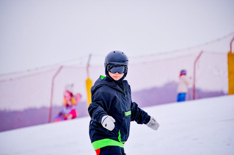 A Person In Black And Green Jacket Wearing Helmet And Goggles