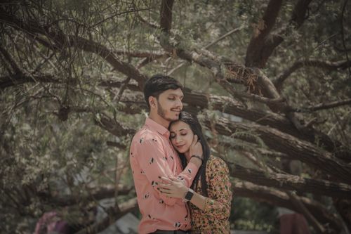 Free A loving couple shares an intimate embrace beneath a tree, symbolizing romance and togetherness. Stock Photo