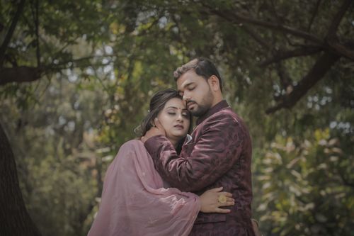 Free A couple embracing outdoors under trees in traditional clothing. Stock Photo