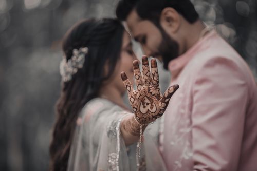 Free Close-up of a bride showing mehndi on her hand while embracing her groom, symbolizing love and tradition. Stock Photo