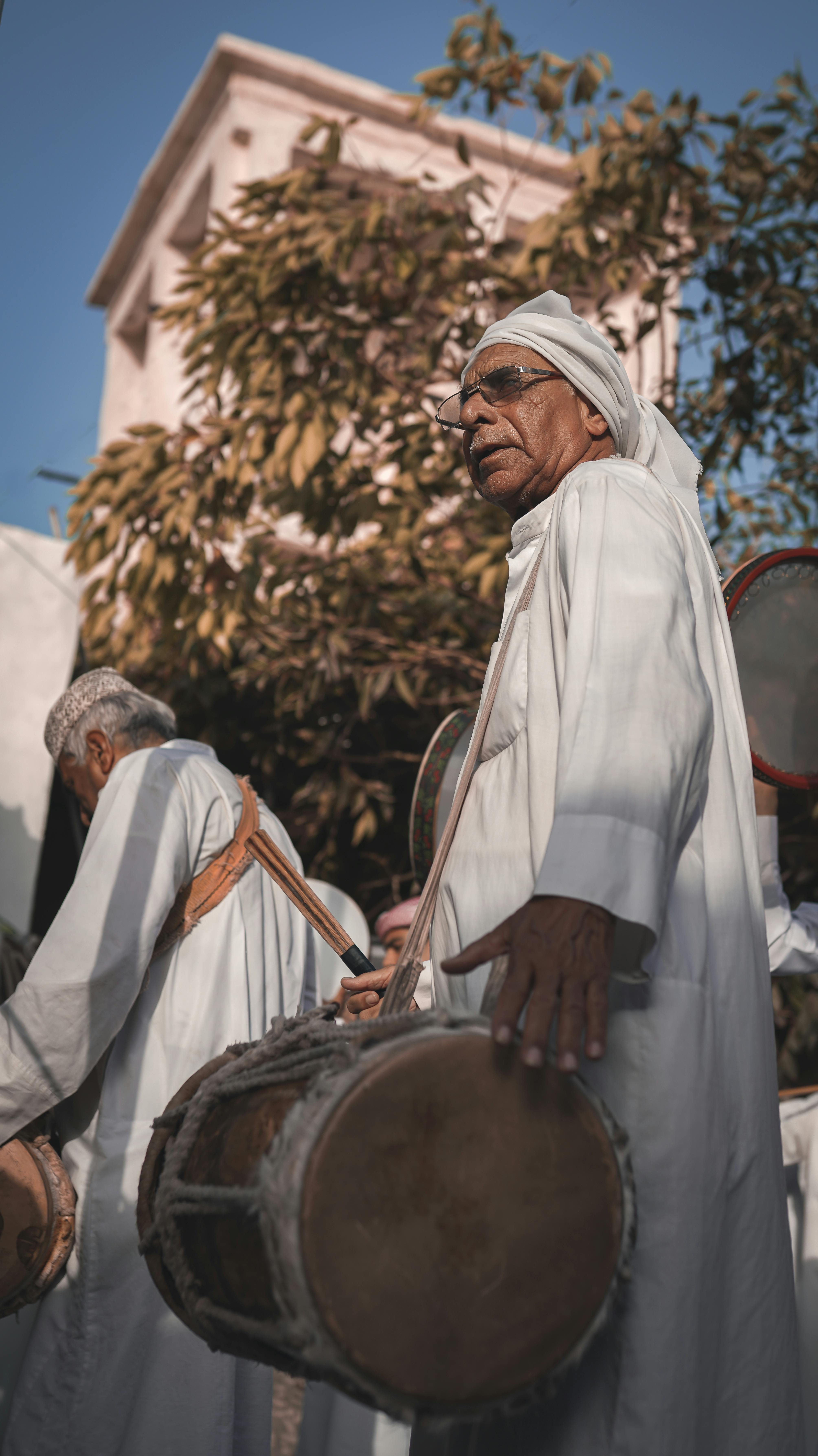 men in white robes playing drums and tambourines