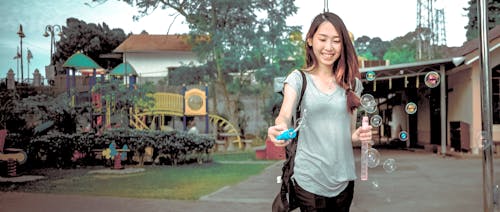 Woman Wearing Gray V Neck Cap Sleeve Top Making Bubbles