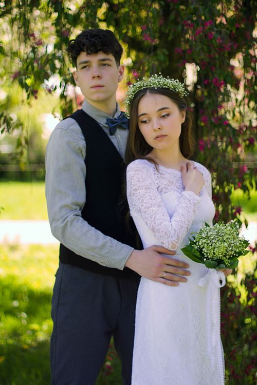 Free Beautiful wedding couple posing romantically in a lush garden setting on their special day. Stock Photo