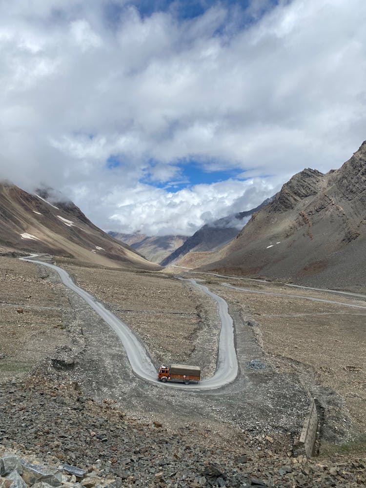 Truck Driving On A Road Between Mountains