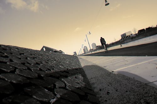 Man Biking on Road Under White Sky