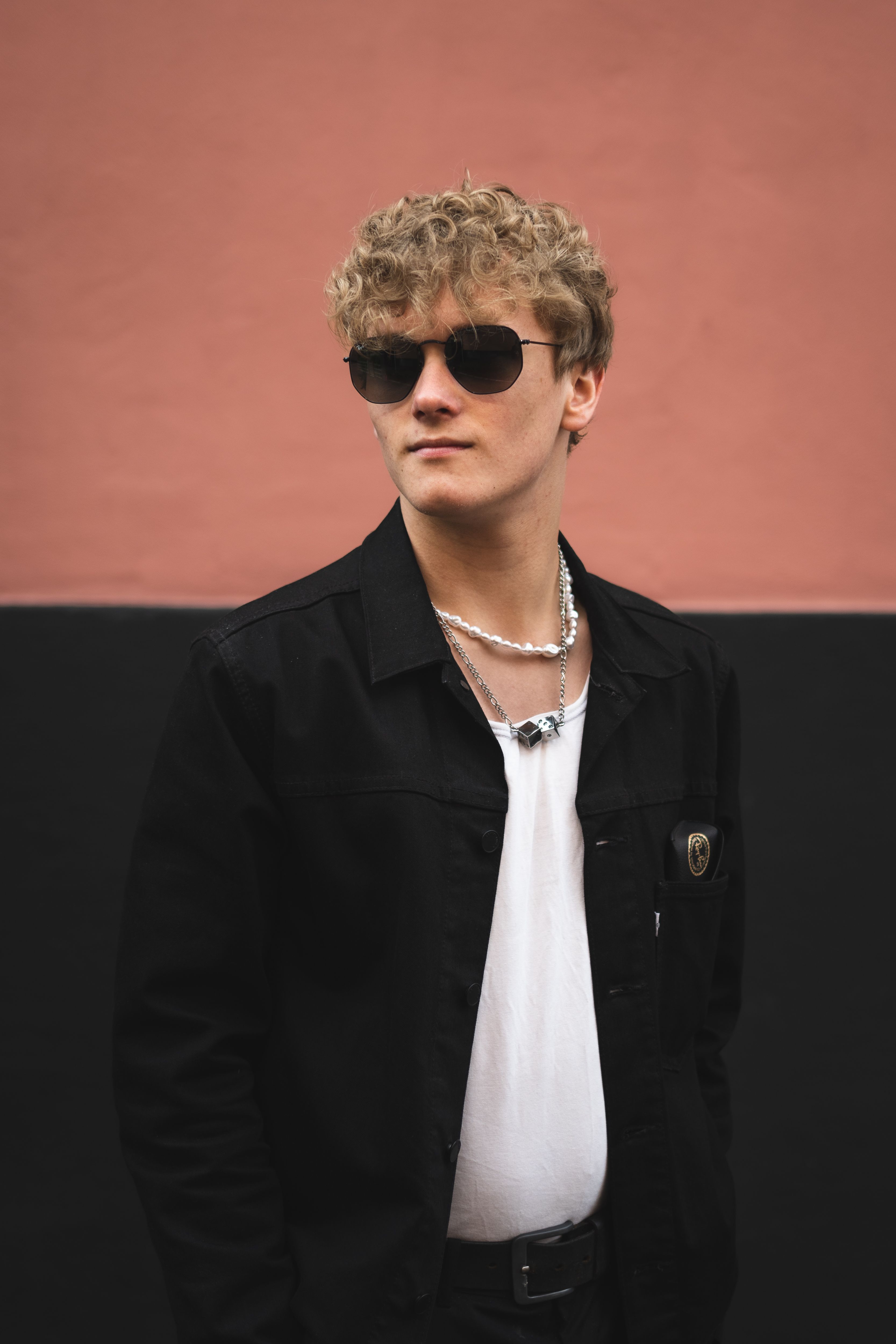 Portrait of a fashionable man in sunglasses and black jacket, Copenhagen street style.