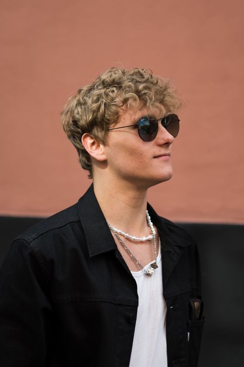 Free Young man with curly blonde hair and sunglasses posing outdoors in Copenhagen. Stock Photo