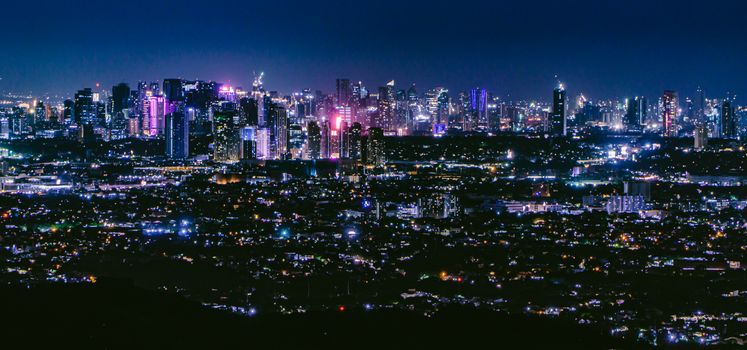Captivating aerial view of a bustling city skyline illuminated at night, showcasing towering skyscrapers and vibrant city lights.