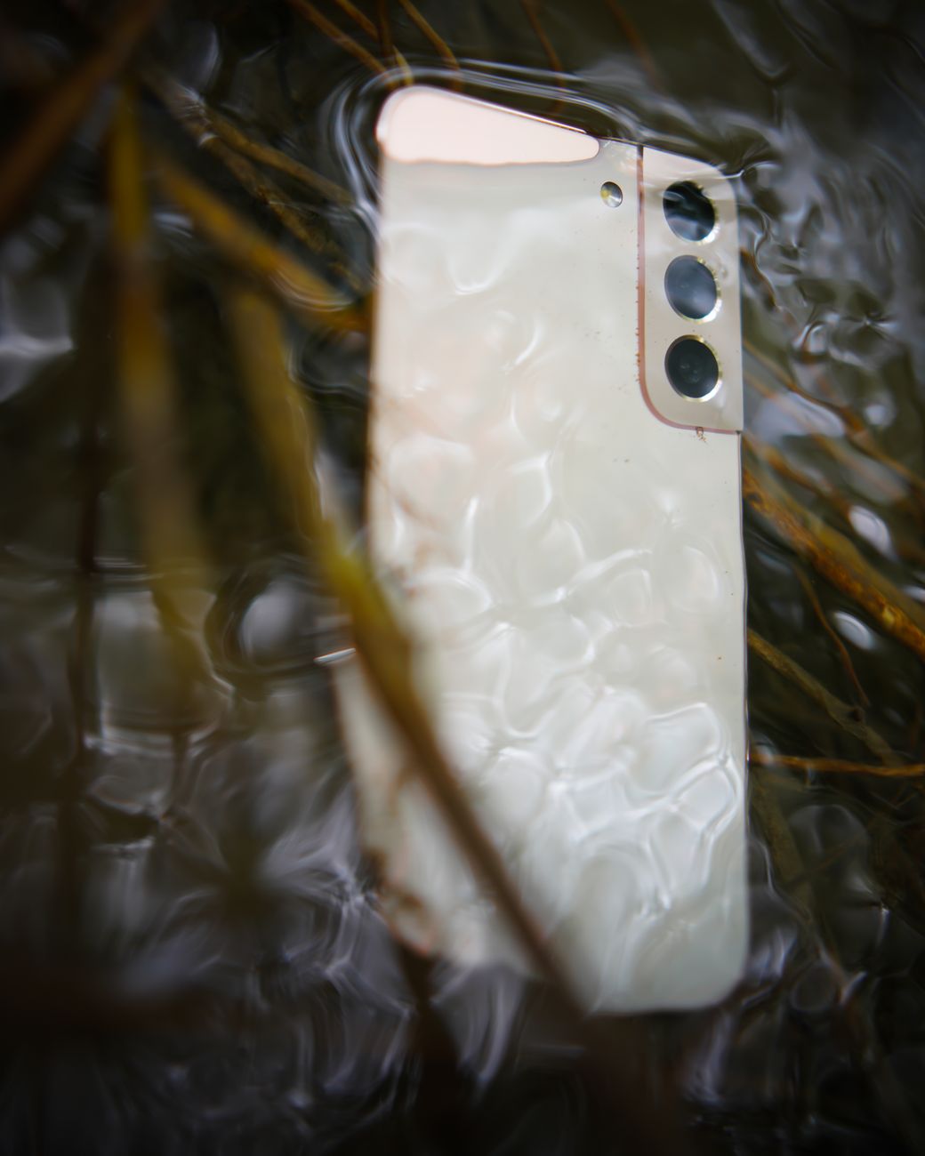 Close-up of a smartphone partially submerged in water with ripples
