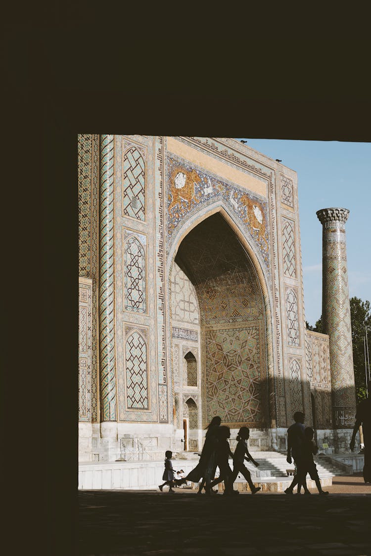 Silhouettes Of People Walking In Front Of The Minaret 