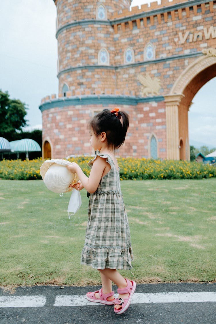 Side View Of A Girl Walking While Holding A Hat