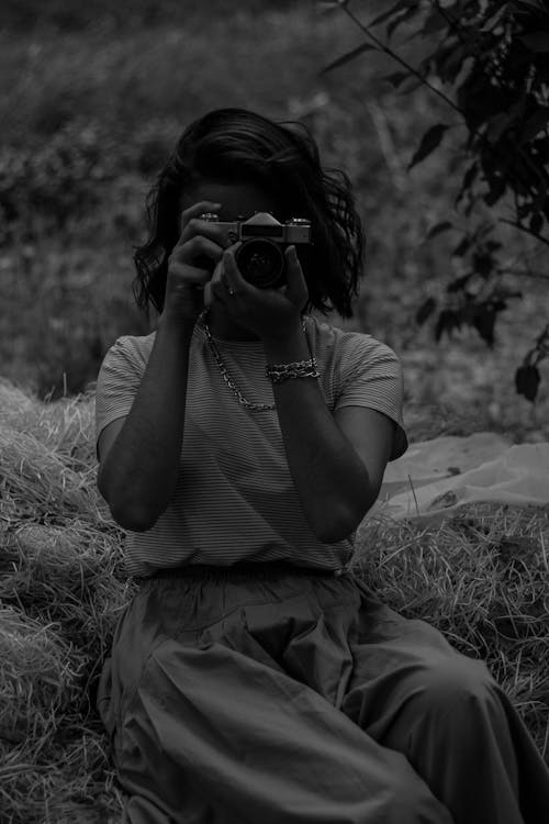 Grayscale Photo of a Woman Holding a Camera
