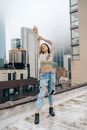 Woman in White Crop Top and Blue Denim Jeans Standing on Gray Concrete Pavement