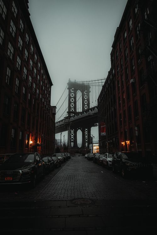 Free A dramatic view of Manhattan Bridge through NYC street at dusk in misty ambiance. Stock Photo