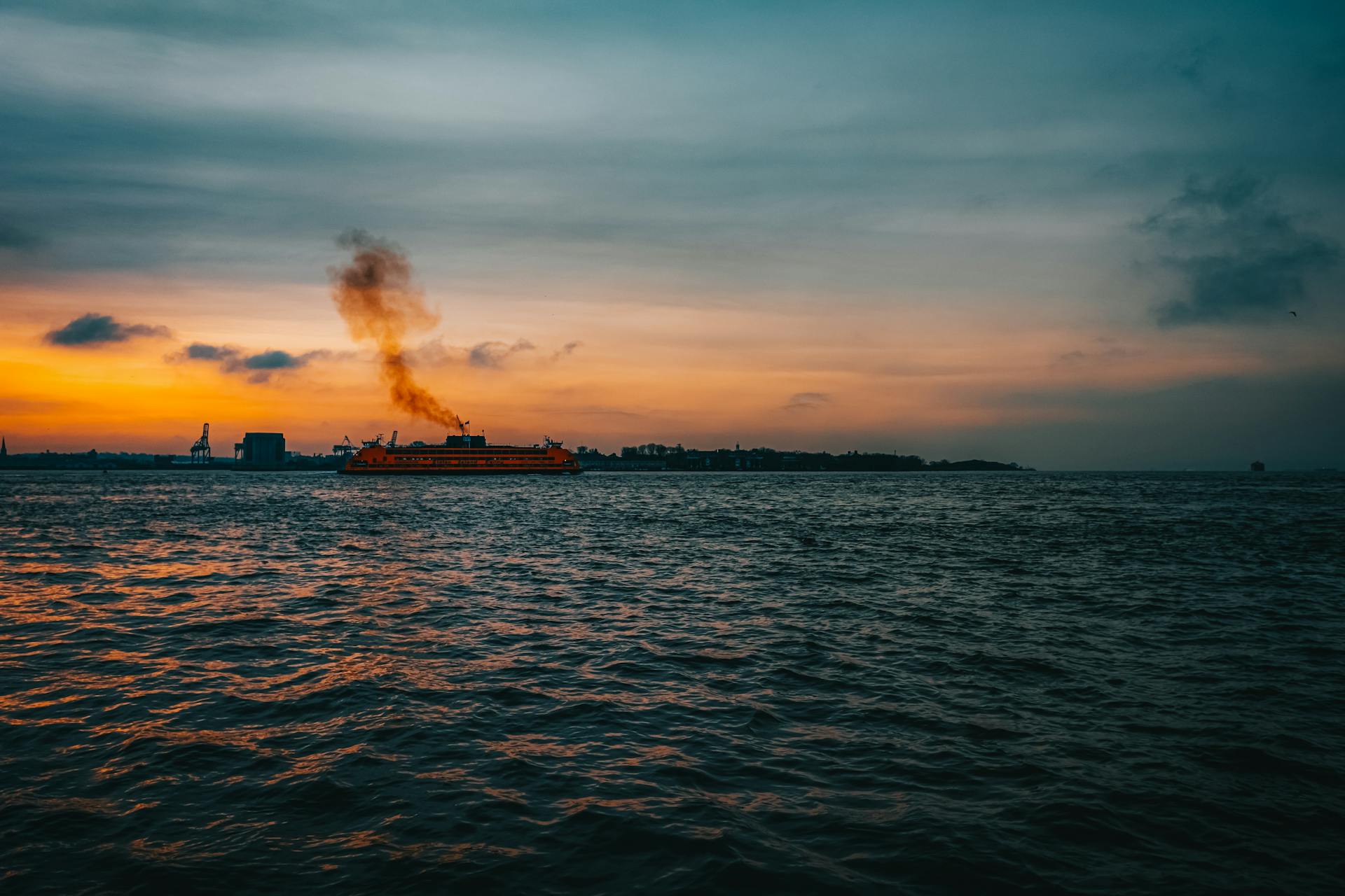 A scenic view of the Staten Island Ferry crossing New York Harbor at sunset.