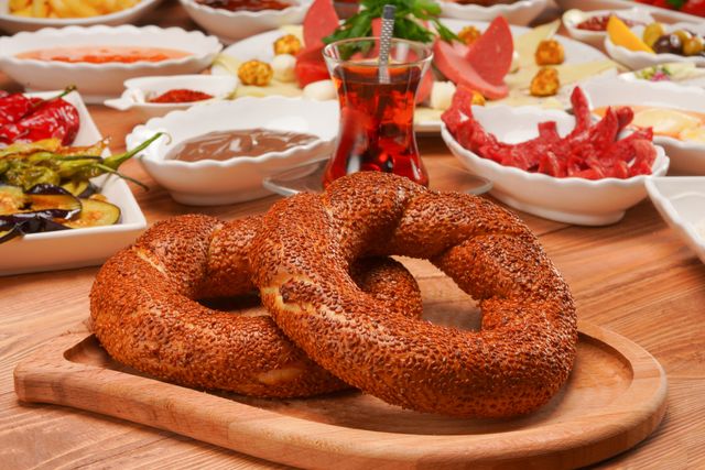 Traditional Turkish breakfast spread featuring fresh sesame bagels and assorted dishes on a wooden surface.