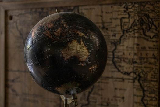 A vintage globe showcases Australia with a sepia world map in the background, offering a classic exploration theme.. pexels, 