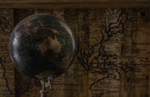 Ancient globe in front of a world map showing Australia