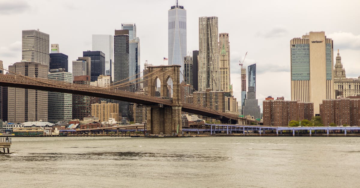 A kayaker navigates the river beneath the iconic Brooklyn Bridge with the NYC skyline in view.